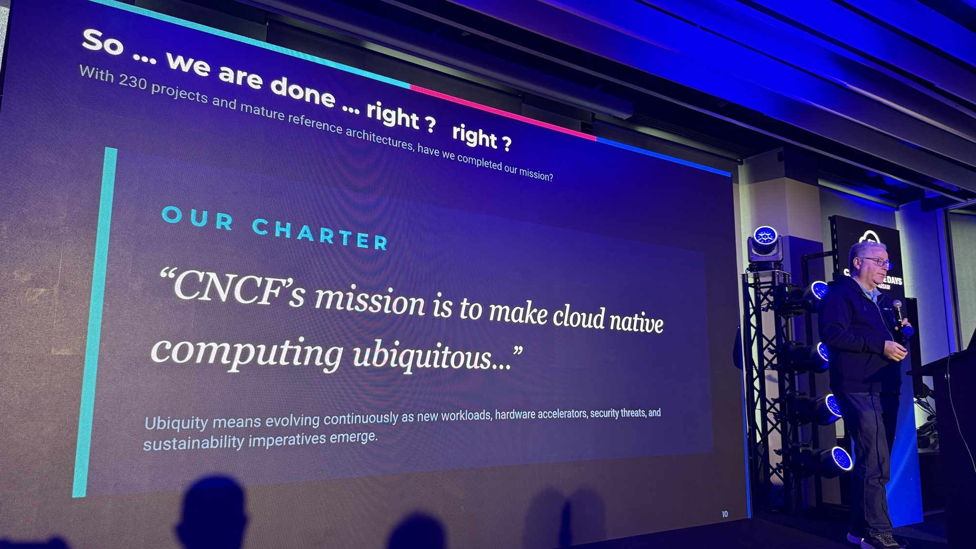 Alex Chircop next to a slide quoting the CNCF charter: CNCF's mission is to make cloud native computing ubiquitous