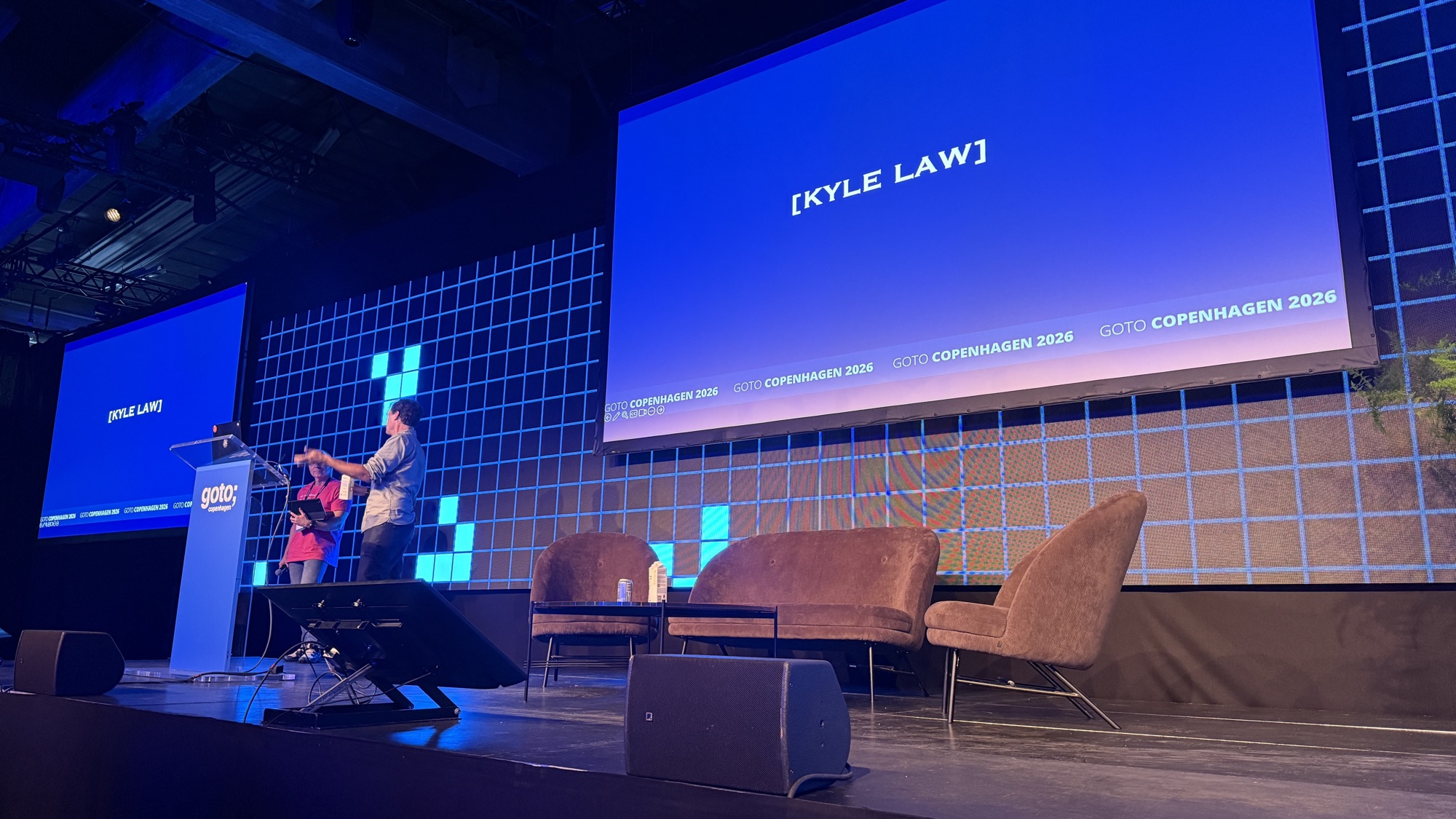 Evan Ratliff during his talk, under a slide reading Kyle Law, as the AI CEO joins the talk live