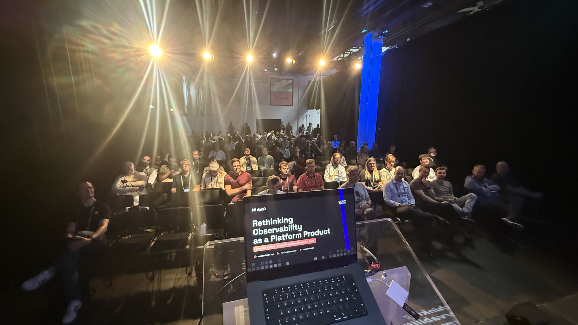 The view from the stage before the talk, with a laptop showing the title slide Rethinking Observability as a Platform Product in front of a seated audience