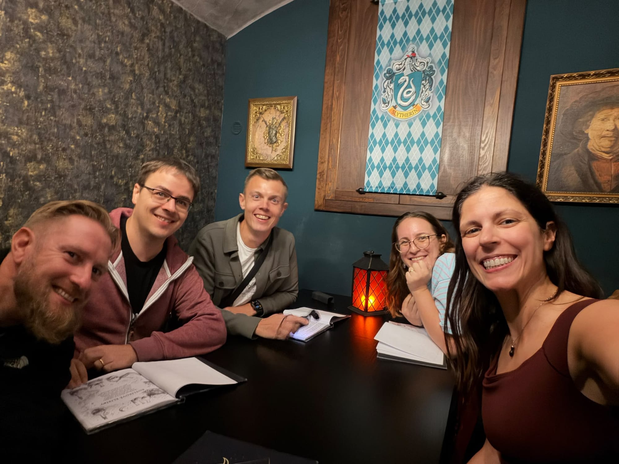 Five of us around a dark table under a Slytherin banner, holding the menus