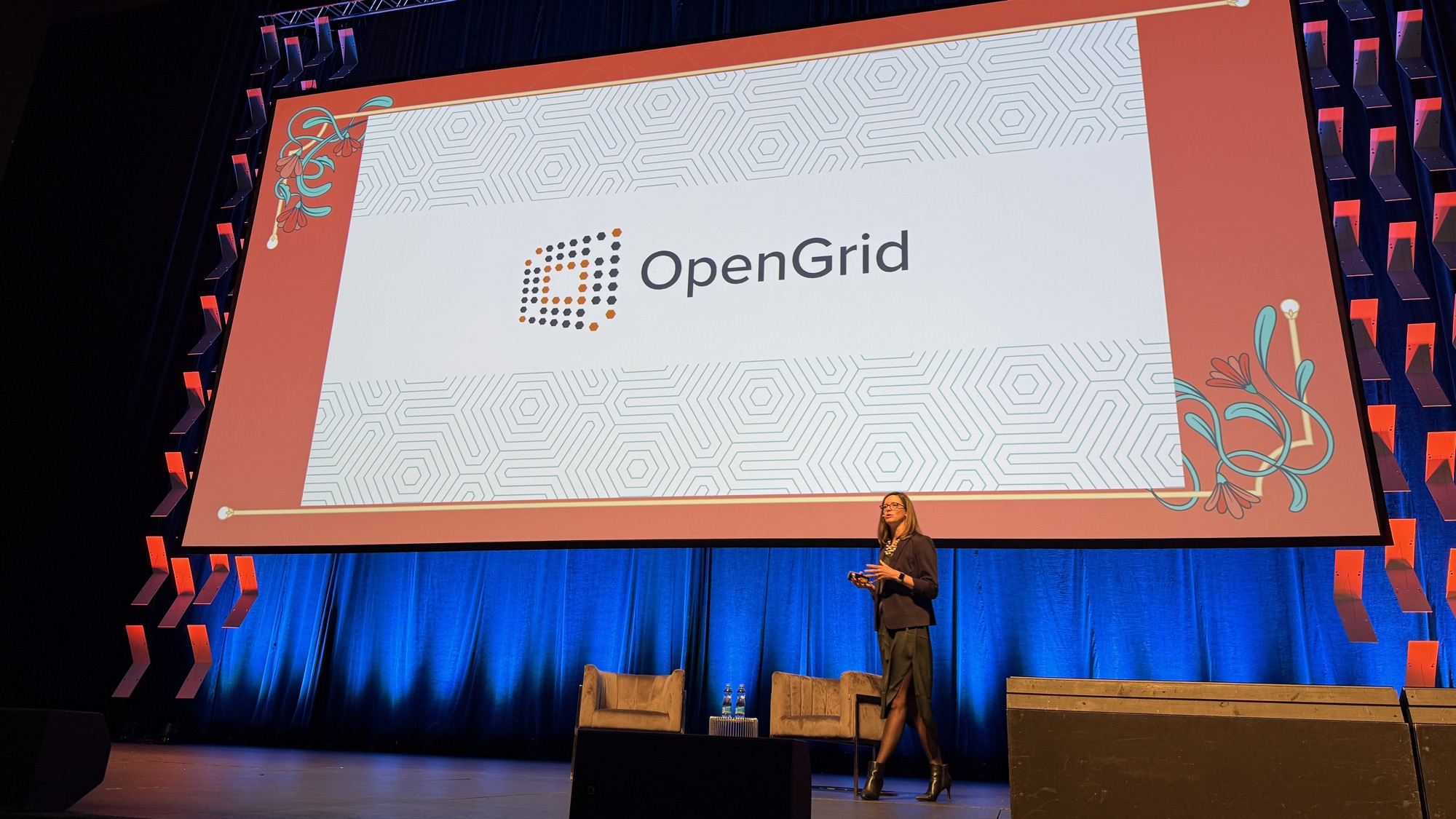 Alice Yake walking across the stage in front of the OpenGrid logo