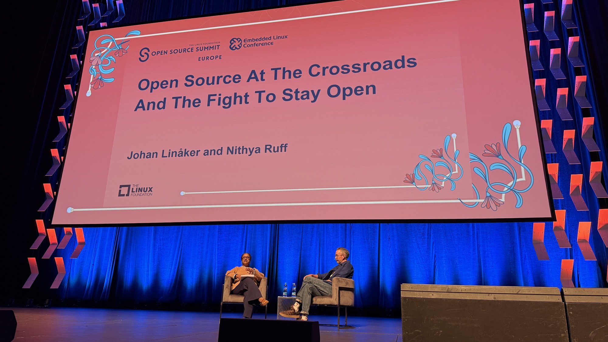 Nithya Ruff and Johan Linåker in armchairs on stage beneath the title Open Source At The Crossroads And The Fight To Stay Open