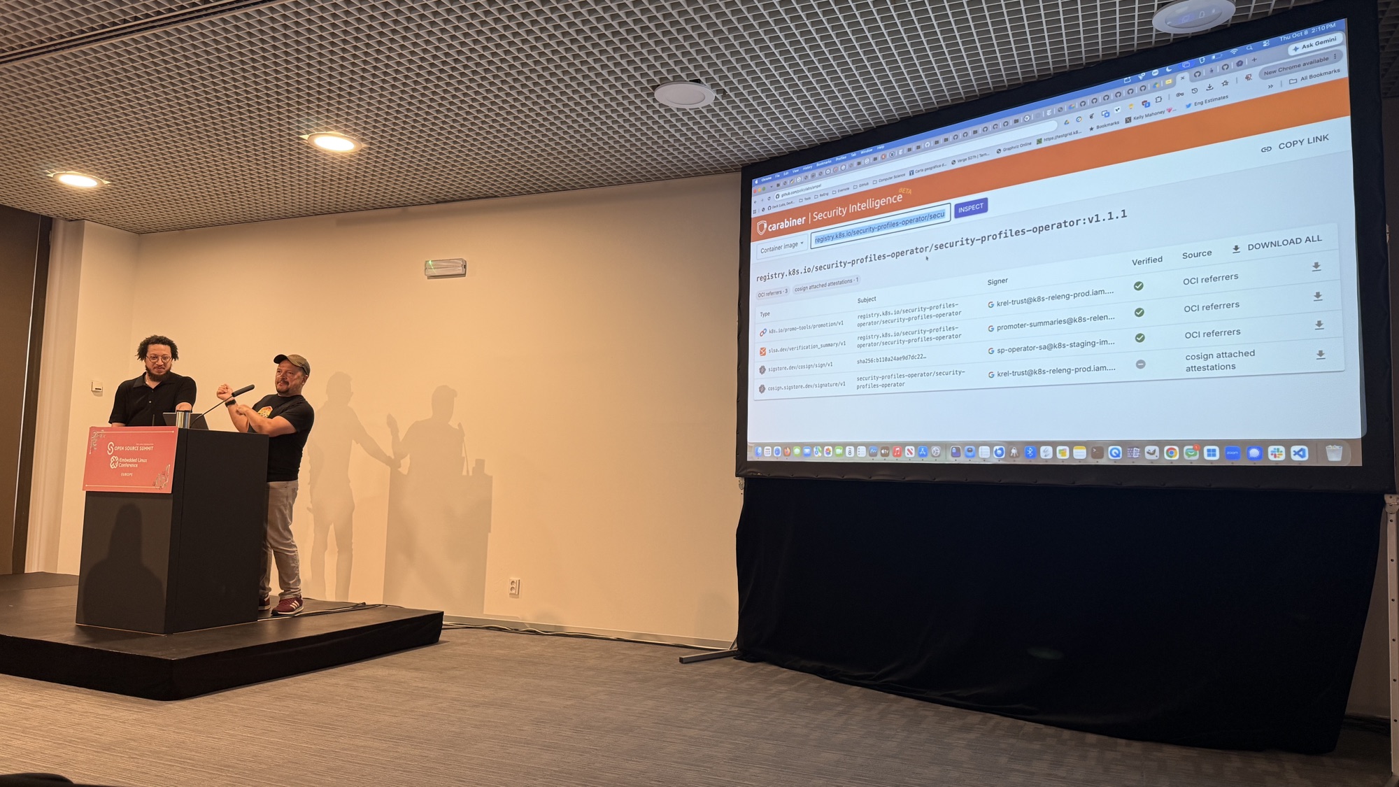 Adolfo and Stephen next to a screen inspecting the security-profiles-operator v1.1.1 image, with a promotion record, a SLSA verification summary and two signatures