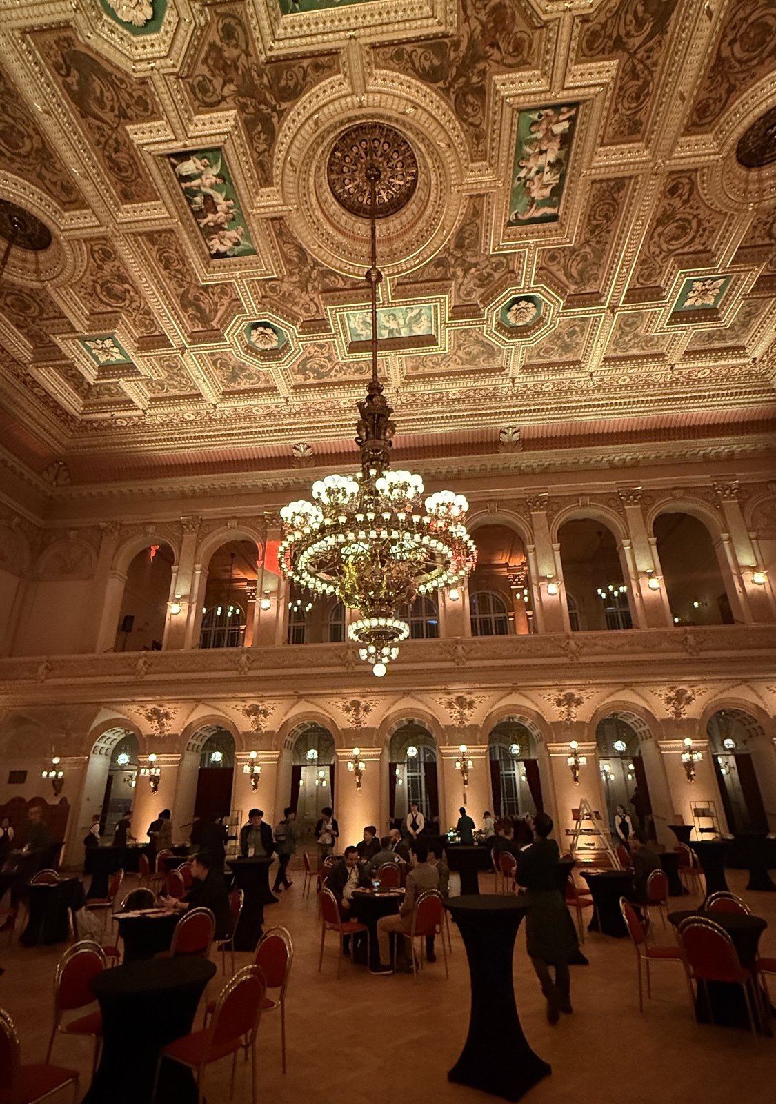 Ballroom at Palác Žofín with a large chandelier, a painted ceiling and cocktail tables