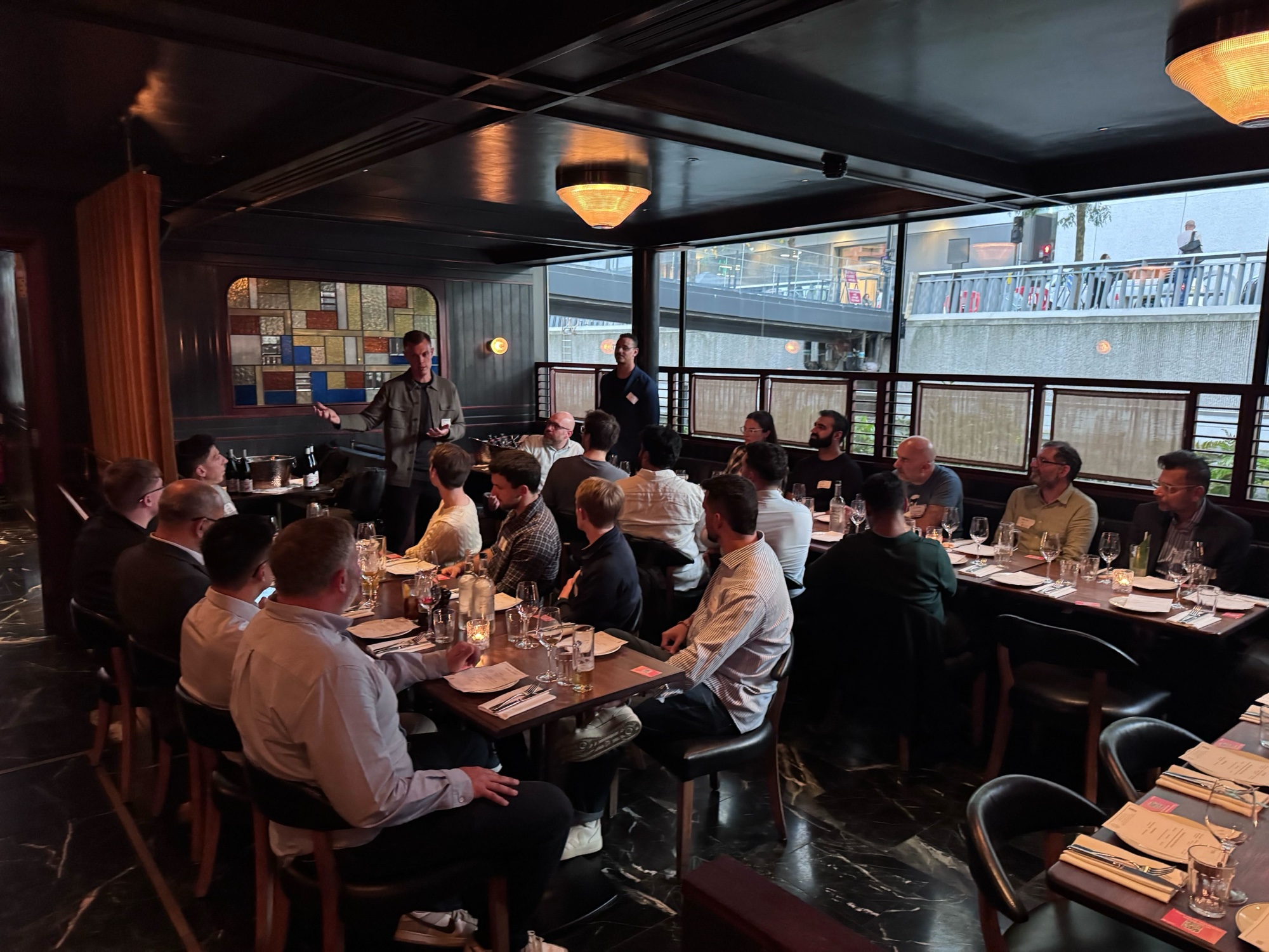 Kasper speaking to a long dinner table of guests in a restaurant